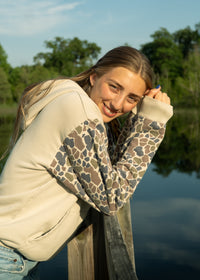 woman wearing oversized tan hoodie with camo sleeves